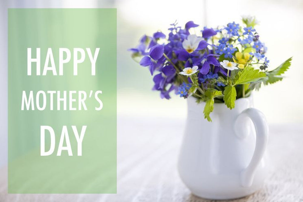 Happy Mothers Day text next to a jug of flowers