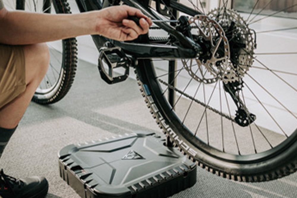 A close-up of a bicycle wheel and rear frame with a person's hand adjusting something.