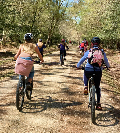 Group of people riding bicycles on a dirt path through a forest