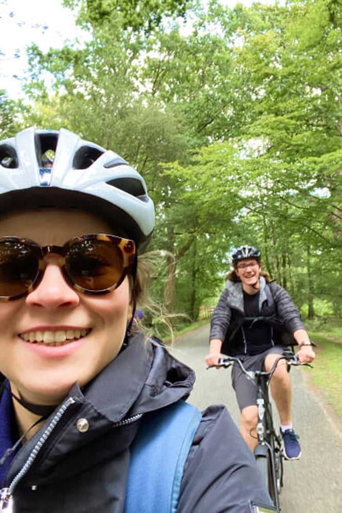 Two people cycling on a path with trees in the background