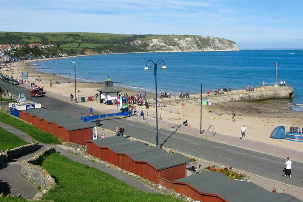 Beach scene with people, buildings, and a coastal landscape.