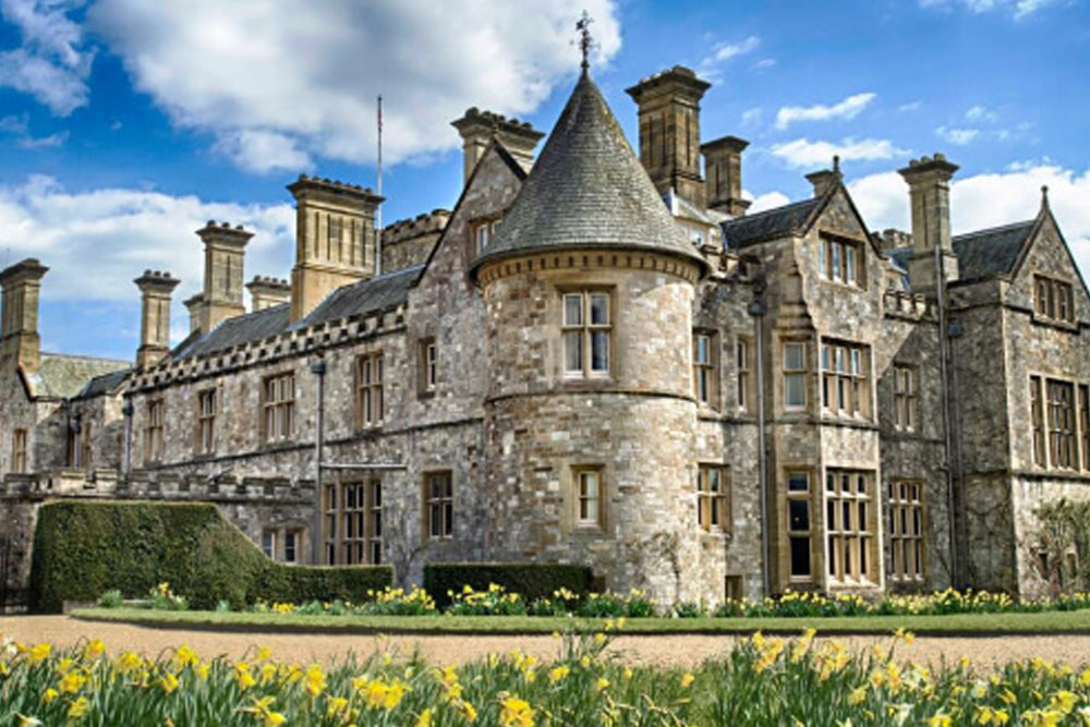 Large stone manor house with a blue sky and clouds in the background