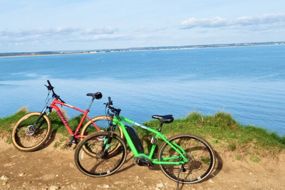 Two bicycles on a dirt path with a scenic view of water and sky.