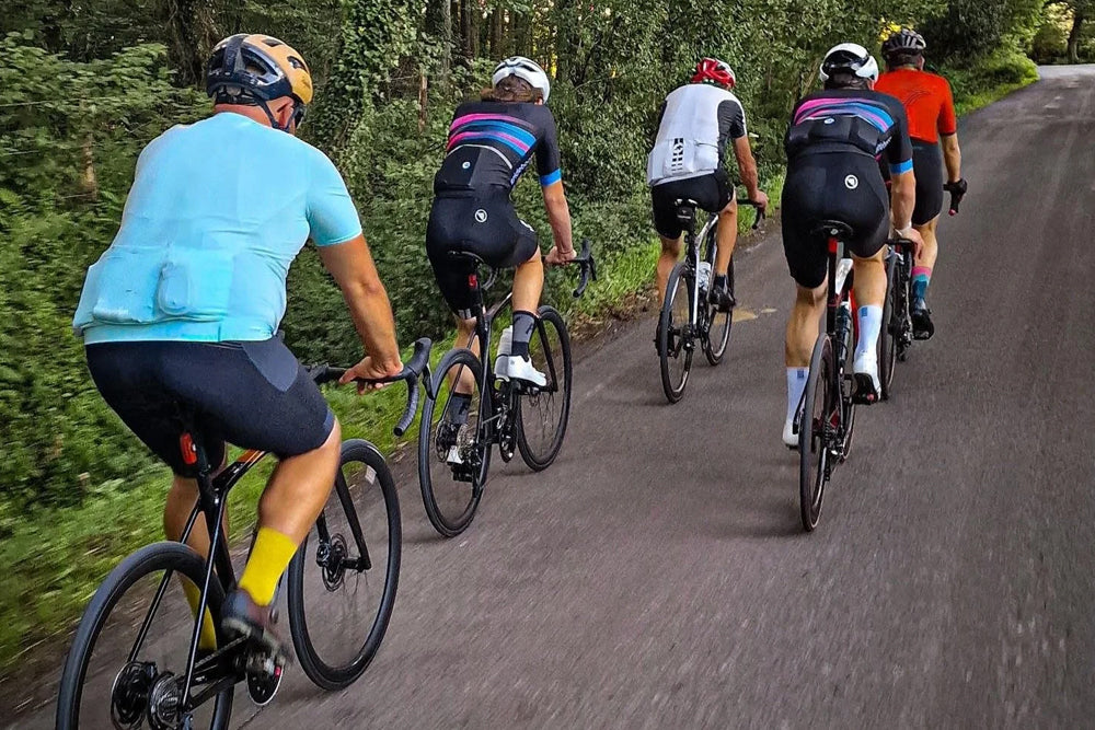 Group of cyclists riding on a road surrounded by trees
