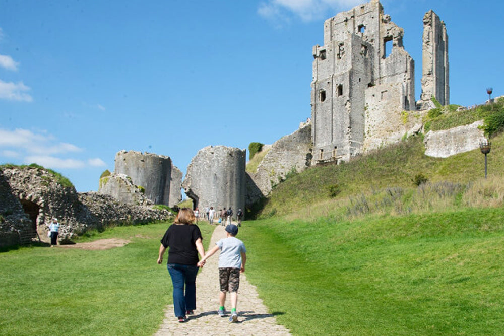 People walking around the ruins of a castle on a sunny day