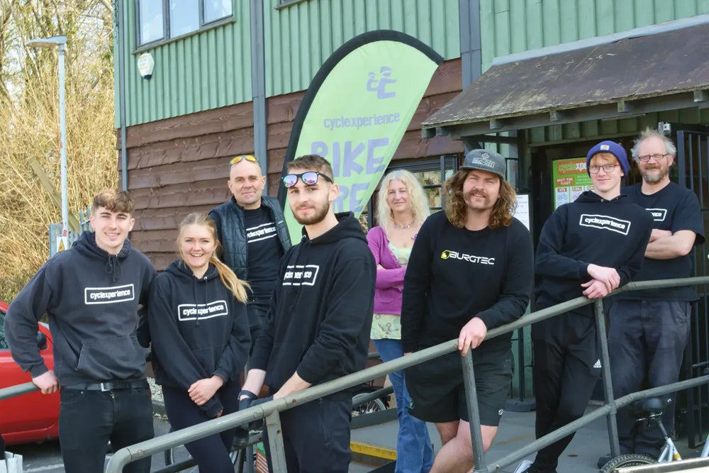 The Cyclexperience team posing together outdoors in front of the store . 