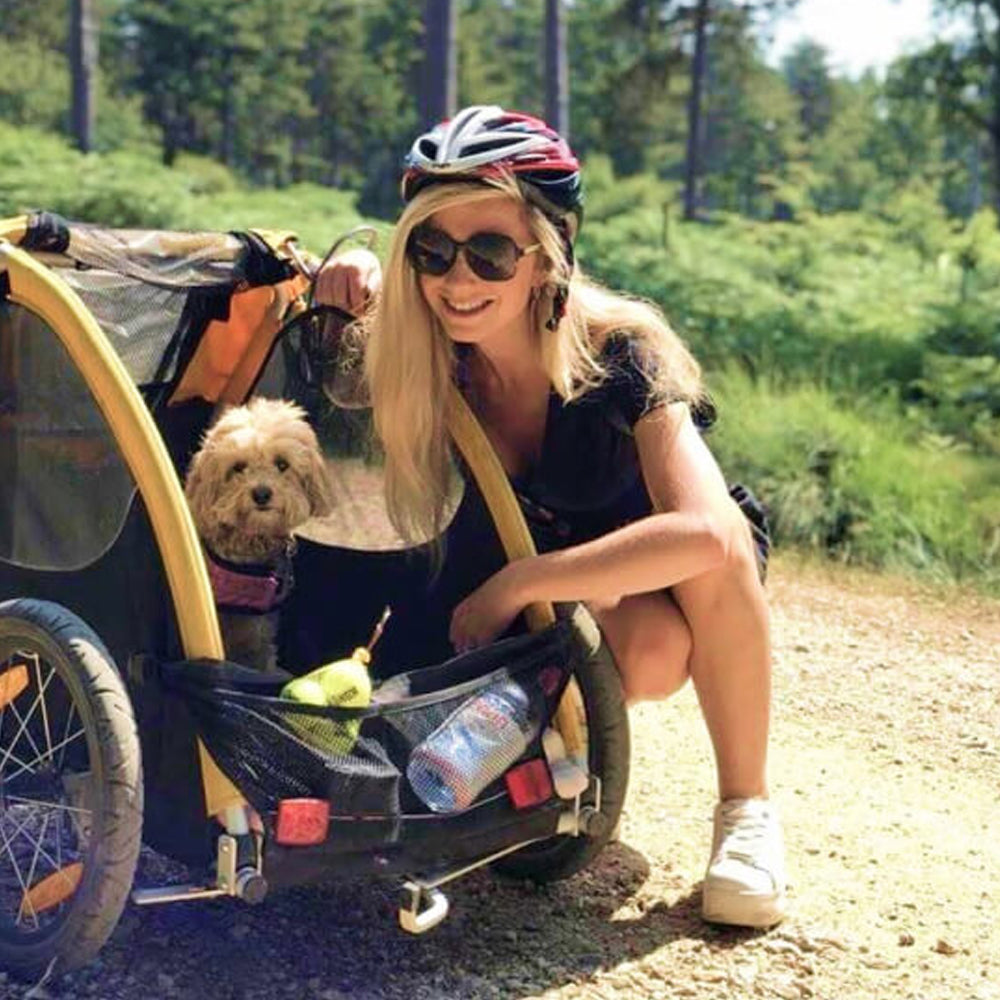 Woman with a dog in a bike trailer on a trail