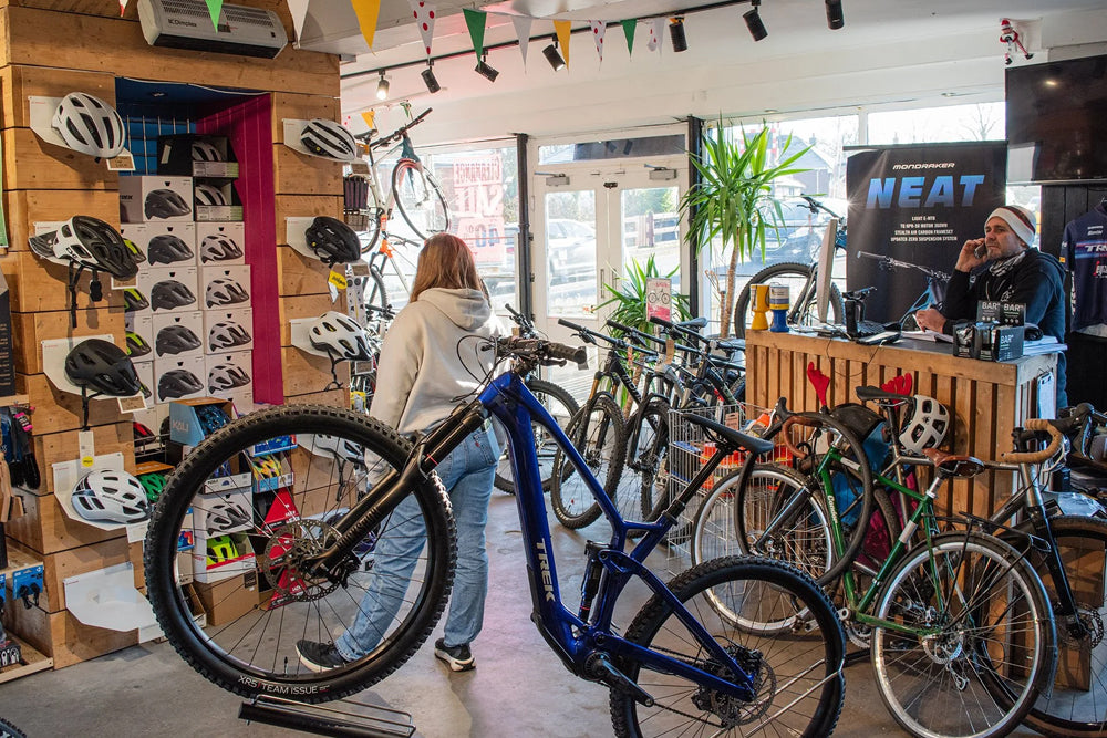 Bicycle store interior with a customer looking at bikes and a staff member behind the counter.