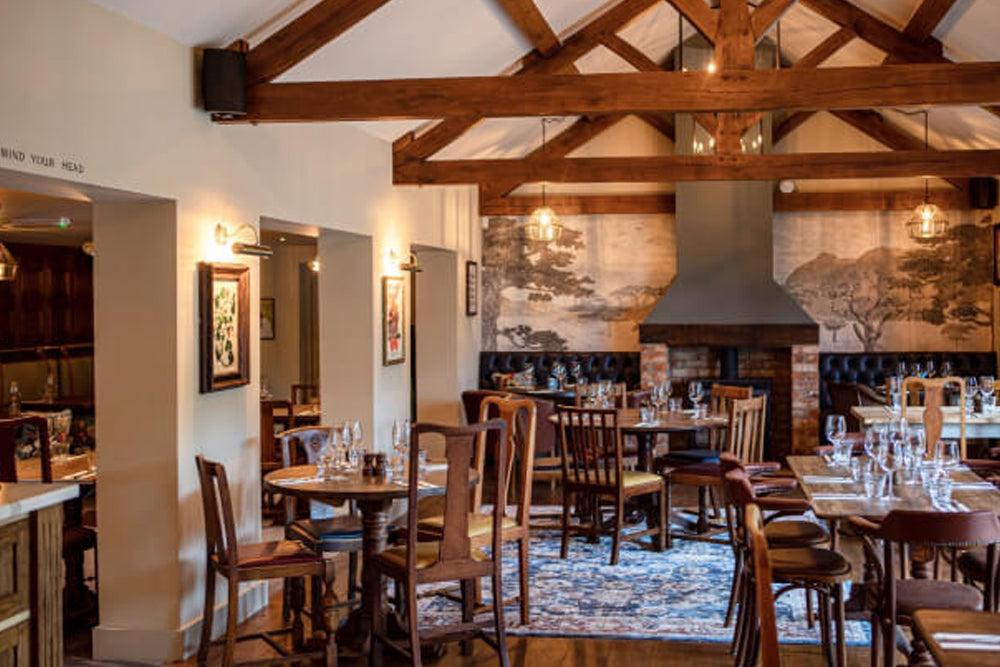 Restaurant interior with wooden beams, tables, and chairs.