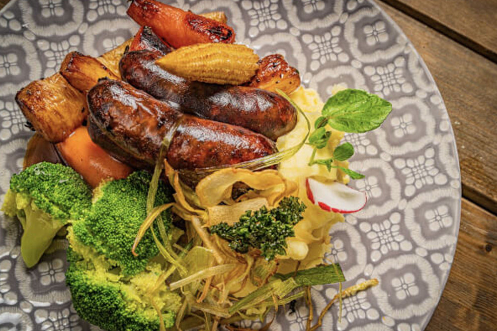 Image of sausages on a plate with roasted vegetables