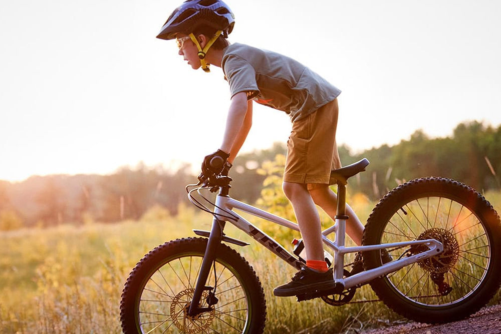 Child riding a bicycle in a field with a helmet on