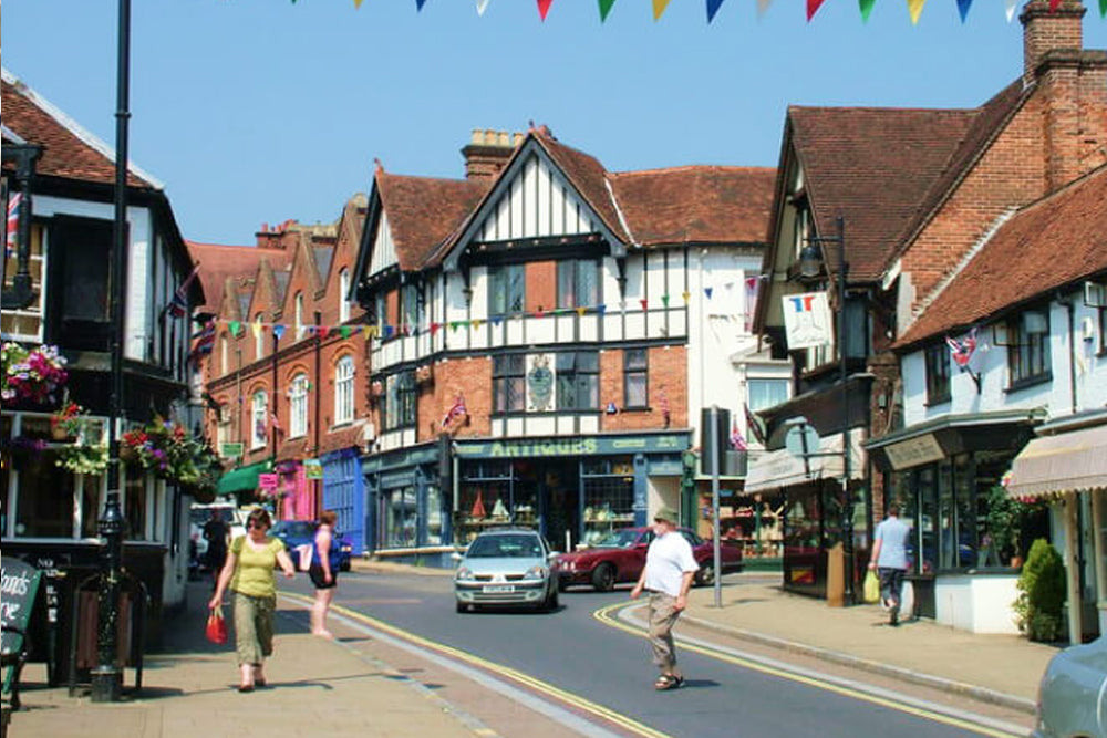 A town with bunting and pedestrians and classic cars