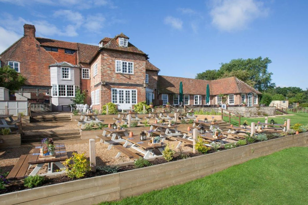 A large brick hotel with white-framed windows and a landscaped garden with dining benches.