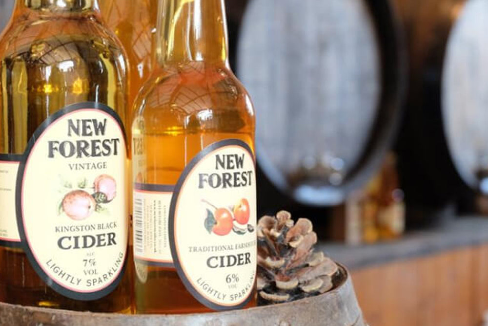 Two bottles of New Forest Cider with a blurred background