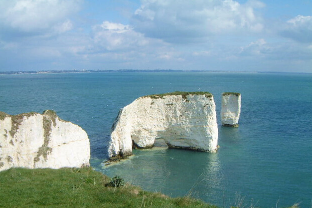 White cliffs of Old Harry Rocks in a coastal landscape with blue sky and sea.