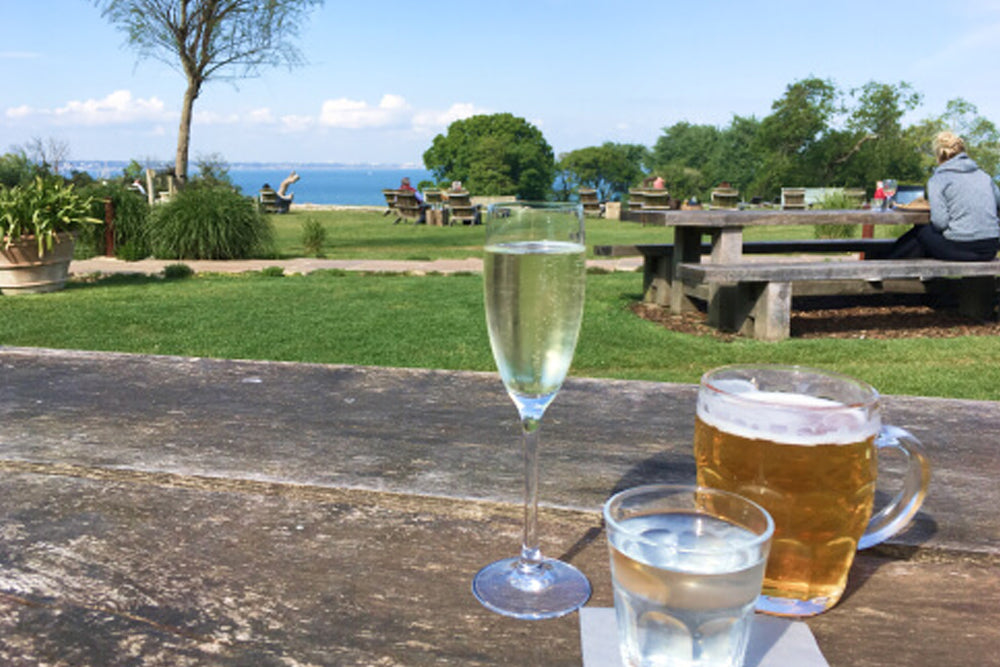 Outdoor setting with drinks on a wooden table overlooking a scenic landscape.