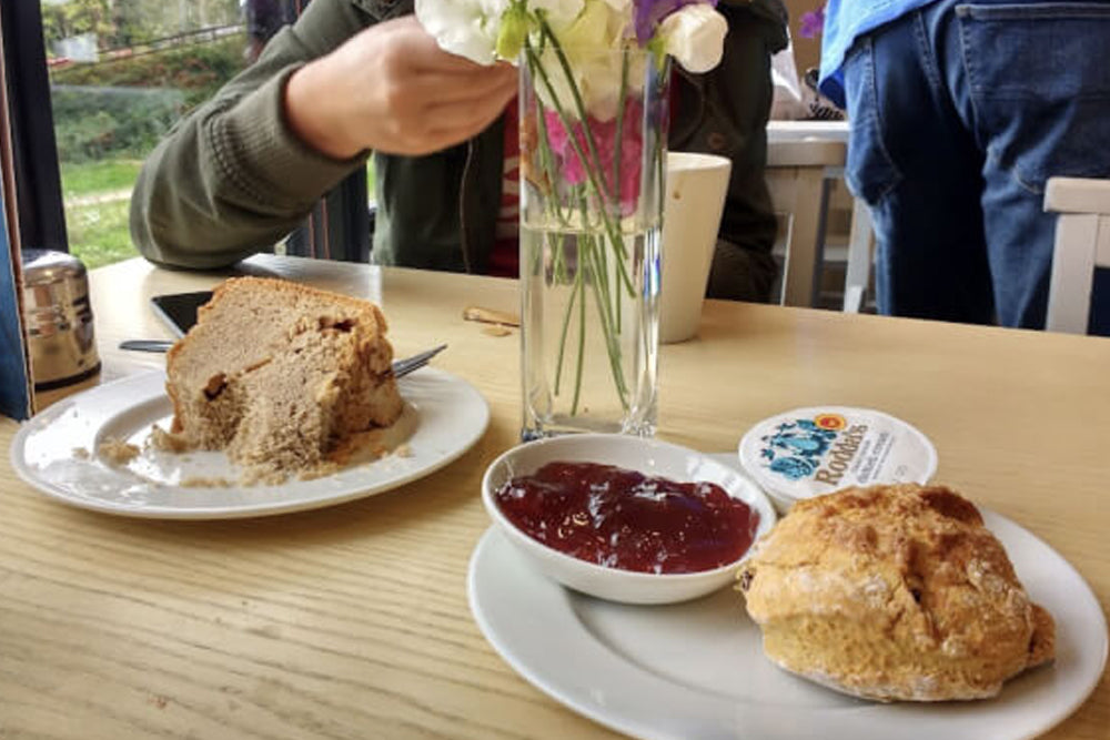 Image of cream tea and cake on a wooden table in a cafe setting