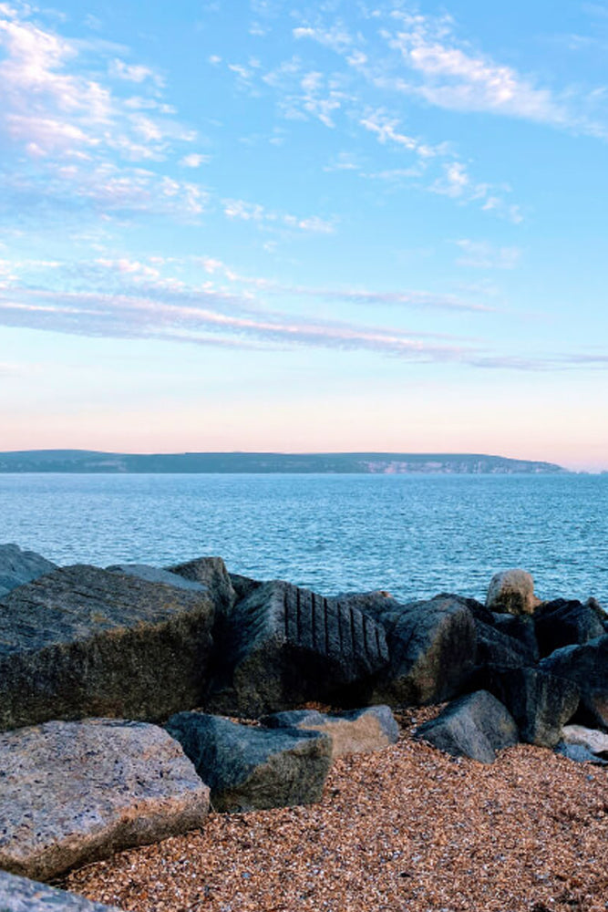 Rocks by a body of water with a clear sky