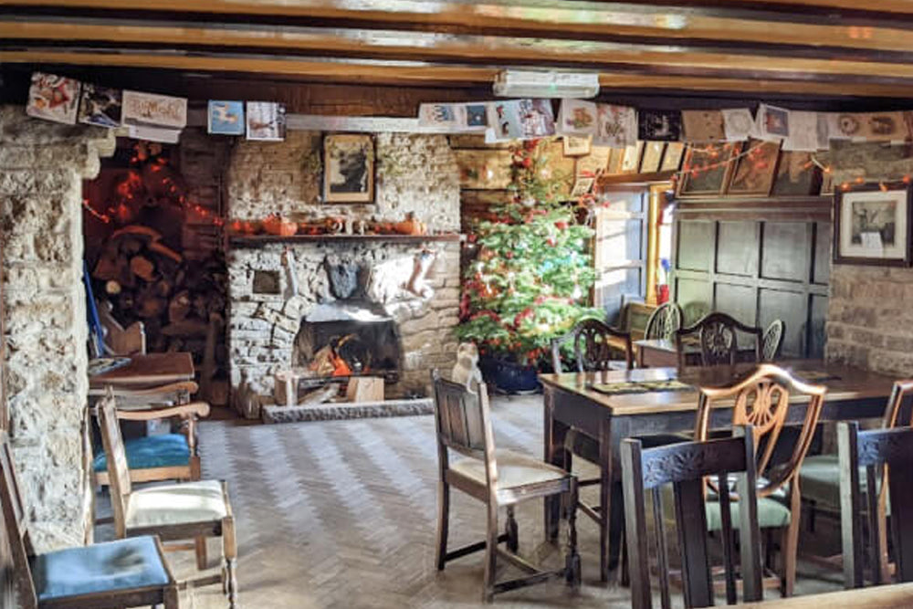 Cozy interior of a rustic dining room with stone fireplace and Christmas decorations.