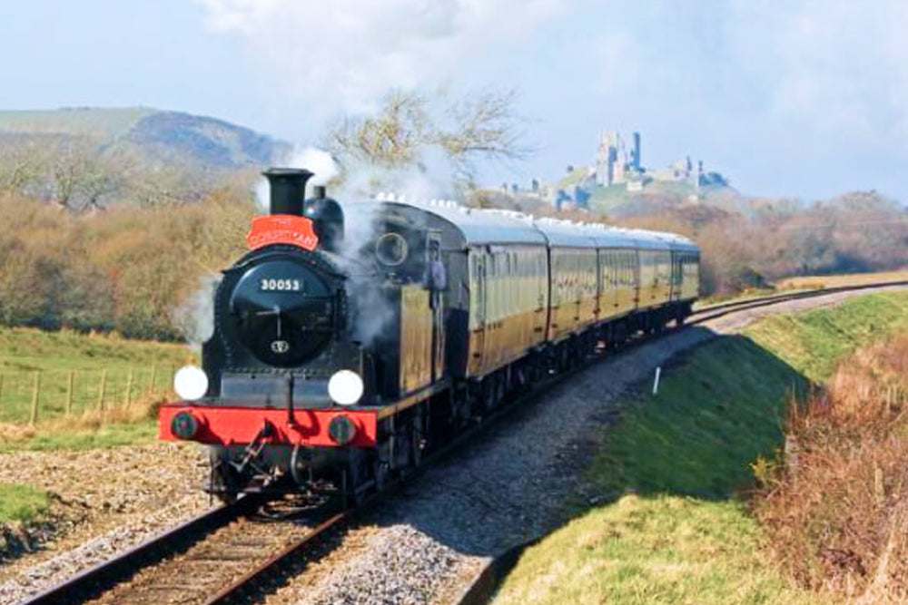 Steam train on tracks with a scenic background