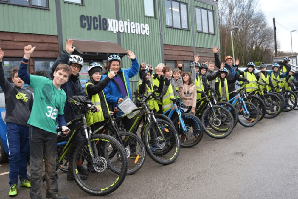 Group of young people with bicycles waving outside Cyclexperience